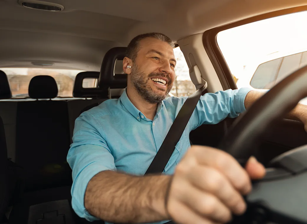 Hombre conduciendo mientras sonríe