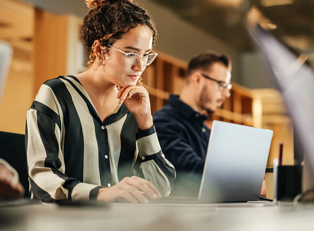 Mujer sentada en una mesa trabajando en su computador portatil